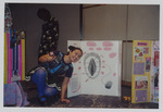 Women's Studies student poses with Another Columbus Makes Another Bogus Discovery poster board by Women's Studies Center, Florida International University